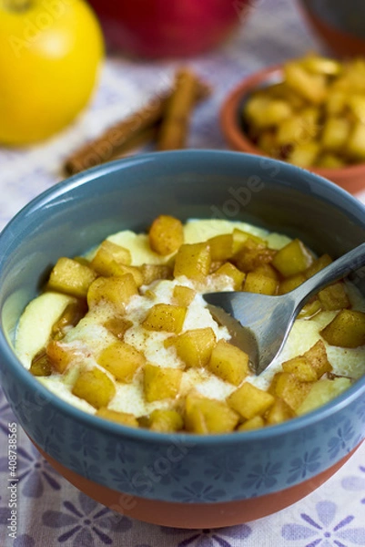 Fototapeta A spoon taking semolina pudding with caramelized apple cubes from a bowl