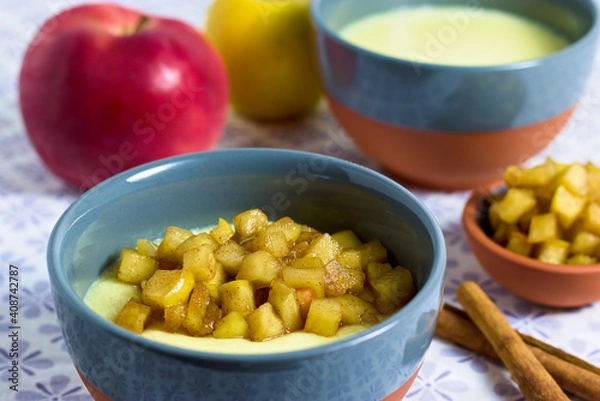 Fototapeta Semolina pudding in a bowl with caramelized apple cubes with apples and cinnamon in background