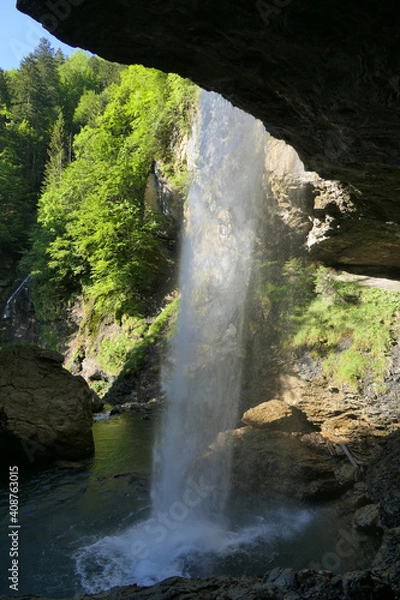 Fototapeta Mighty beautiful waterfall taken from a cave, between Glarus and Klausenpass in the Swiss Prealps
