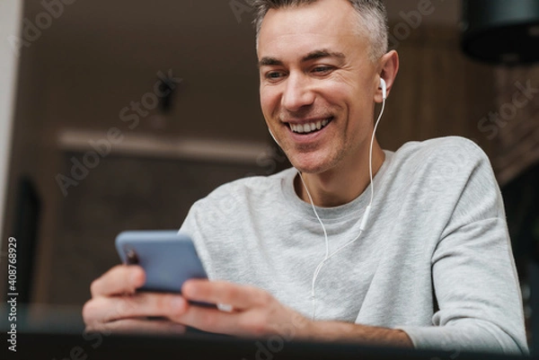Obraz Close up of a smiling man listening to music with earphones