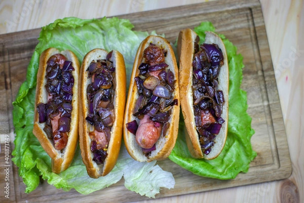 Obraz hot dogs with fried onions on lettuce leaves