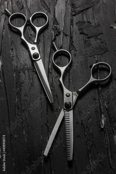 Fototapeta Metallic barber scissors on top of dark background.