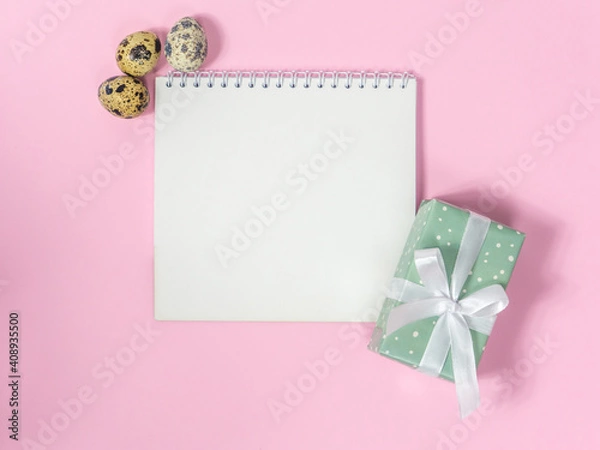 Obraz Blank sheet of paper for text surrounded by quail eggs and gift box on pink background. Preparation for easter. Happy Easter Holiday card with space. Easter shopping list. Easter holiday concept.