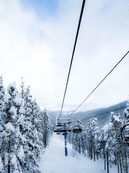 Fototapeta A view from a ski lift on a snowy mountain