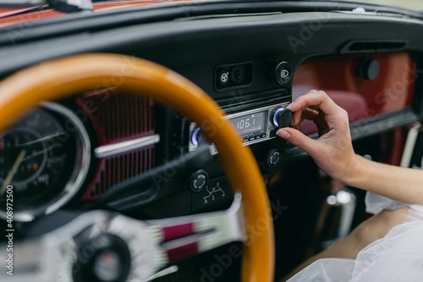 Fototapeta A man tunes the radio in a retro car.