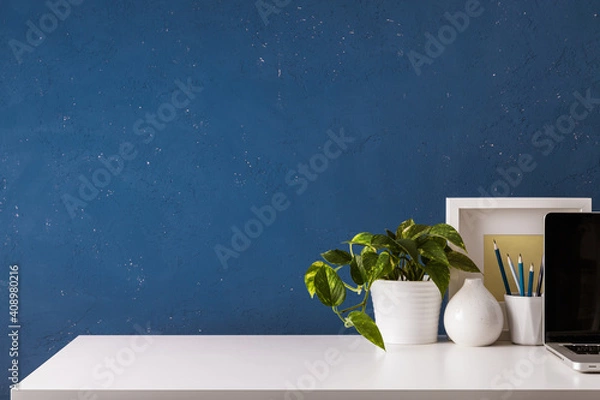 Obraz Home office desk with, supplies, objects and blue wall.