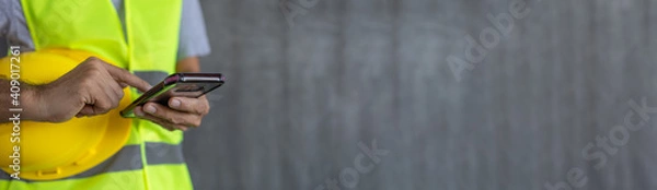 Fototapeta construction worker hands touch screen using smartphone on cement wall background with copy space
