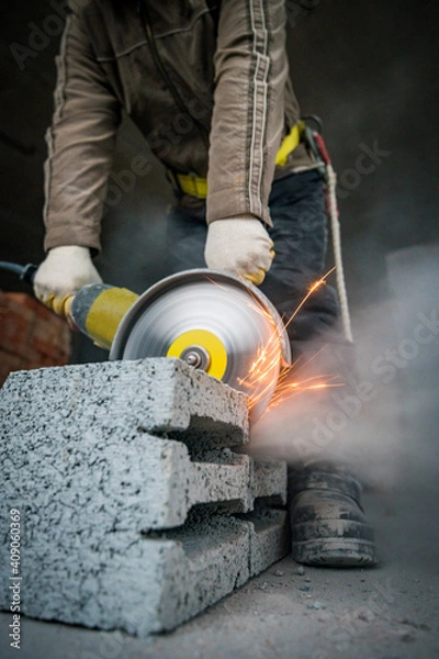 Fototapeta a builder saws a building block with a grinder