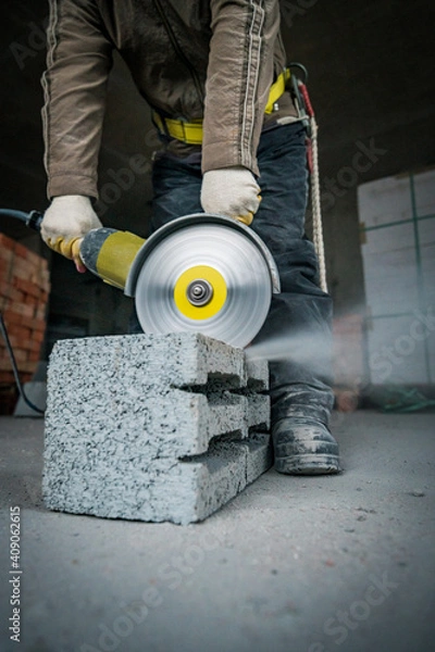 Fototapeta a builder saws a building block with a grinder