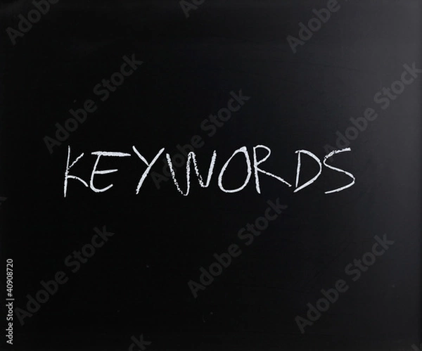Fototapeta The word "Keywords" handwritten with white chalk on a blackboard