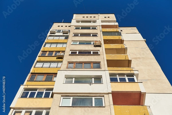 Fototapeta High apartment building of Soviet construction bottom view of a tall panel house isolated on vivid blue sky background in Sofia, Bulgaria, Eastern Europe