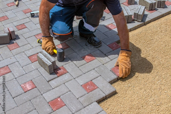 Fototapeta A builder installs concrete blocks for sidewalks in the courtyard of a country house. Selective focus.