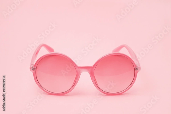 Fototapeta Pink glasses on a pink background close-up in the center of the frame for Valentine's Day.