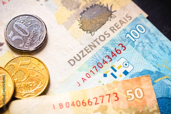 Fototapeta In this photo illustration the detail of the two hundred reais note and a few real coins, twenty-five cents. The Real is the current money in Brazil.