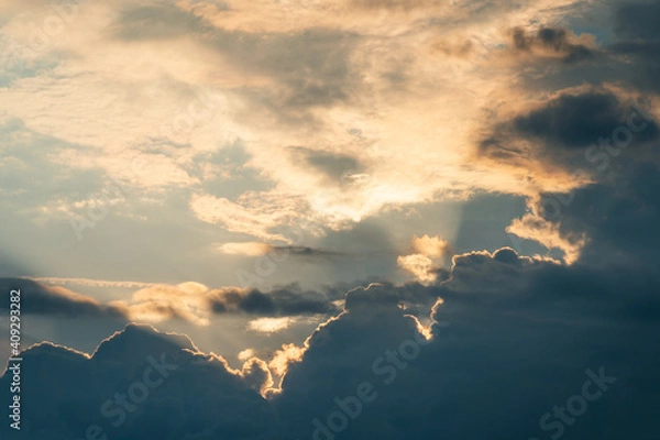 Obraz Sunbeams filter through cumulus nimbus under high altitude clouds.