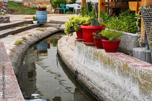 Obraz red pots with flowers on the waterfront canal