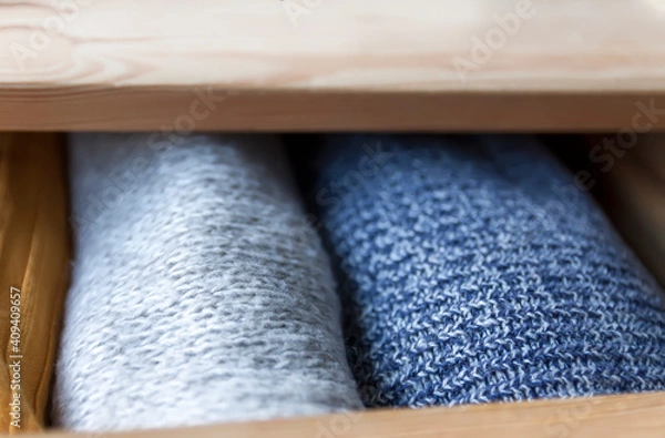Fototapeta Open wooden dresser drawer with warm knitted woolen clothes. Home vertical storage. Wardrobe organizing.