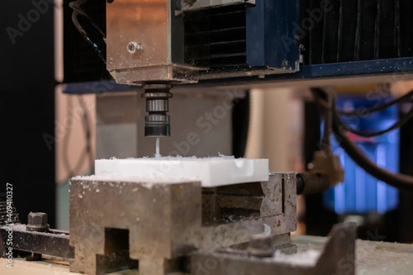 Fototapeta Automatic cnc turning milling machine cutting white acrylic artificial stone workpiece at factory, plant, exhibition: close up. Stoneworking, engraving, industrial, technology, manufacturing concept