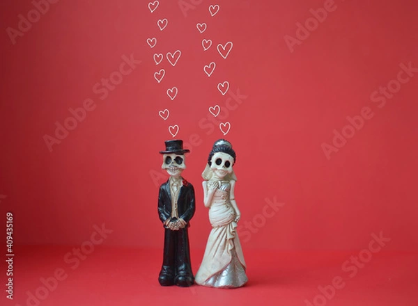 Fototapeta A close-up shot of two skeletons with hearts over their heads for Day of the Dead, Halloween, or Valentine's Day against a bright red background. Copy space