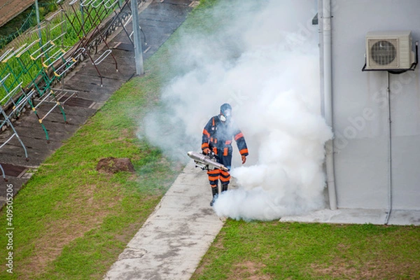 Fototapeta Healthcare worker using Fogging machine spraying chemical to eliminate mosquitoes and kill larvae to fight against the spread of dengue fever, Zika virus or Malaria at a residential area.