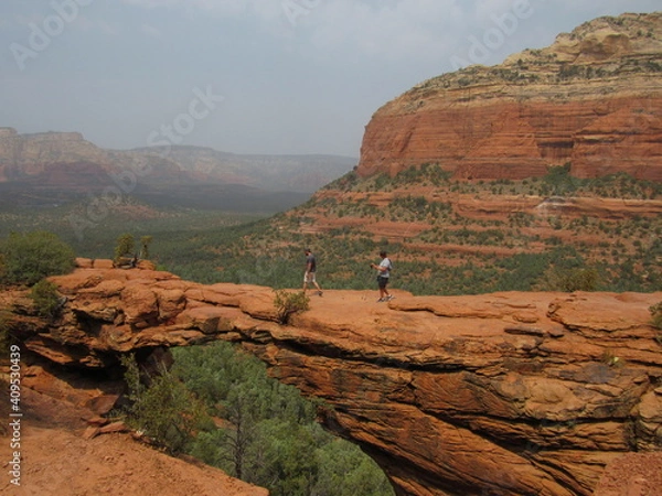 Fototapeta An unrecognizable person on Devil's Bridge, the natural arch formation, with red rock mountains in the background located in Sedona, Arizona