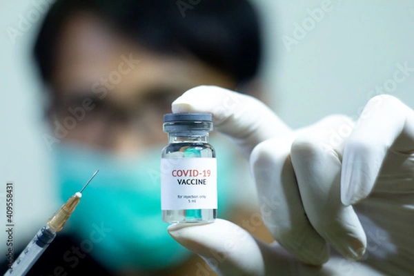 Obraz man showing covid-19 vaccine bottle and the syringe