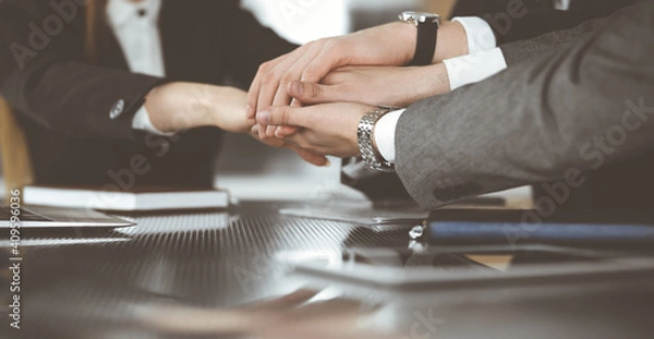Fototapeta Unknown business people group joining hands in modern office. Businessmen and women making circle with their hands as a team, close-up