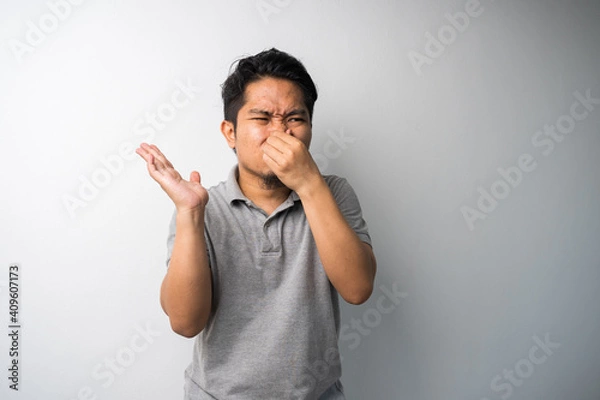 Obraz Man closing nose, stink face expression. Isolated portrait selective focus.