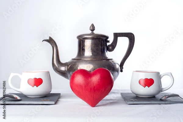 Fototapeta Teapot and two cups with hearts painted on them., and a red love heart in the middle. Romantic tea time or breakfast. Concept of love and Valentines day 