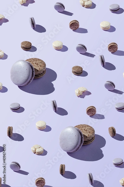 Fototapeta Macaroon patern of different sizes, chocolate, coconut and berry cookies on a lilac, purple background