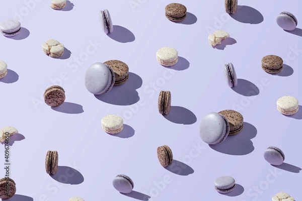 Fototapeta Macaroon patern of different sizes, chocolate, coconut and berry cookies on a lilac, purple background