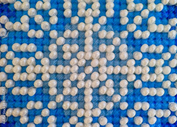 Fototapeta Closeup of Blue threads cross stitch pattern with white beads.