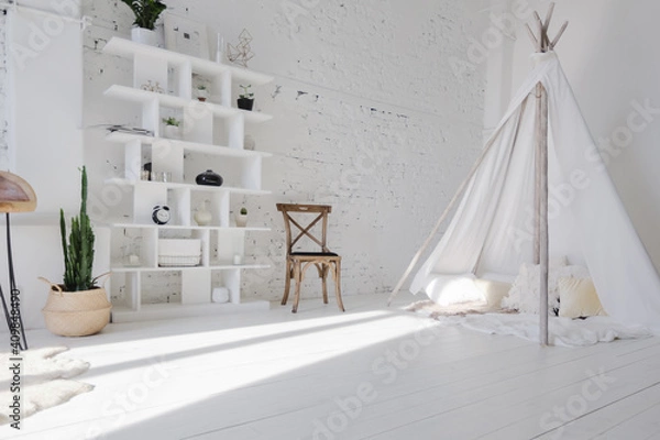 Fototapeta Spacious stylish modern trendy loft apartment in white and light colors. brick wall, wood floor, shelving, pallet bed and teepee-shaped children's house. everything is white with gray tints.