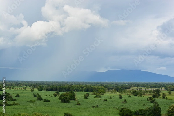 Fototapeta clouds over the mountains with raining in the front of it white and gray clouds and strong winds green farm land landscape in Thailand