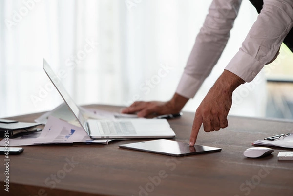 Fototapeta Portrait of young handsome confident businessman in suit using digital tablet