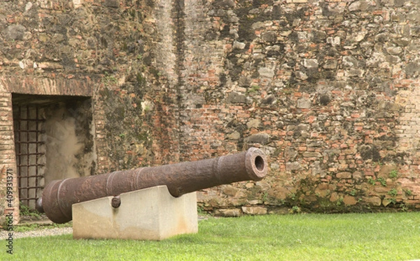 Fototapeta old cannon in front of stone wall