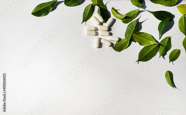 Fototapeta 
Border corner made of white pills and fresh green leaves. Template for the text of the announcement of the note. Health and nutritional theme. Minerals and vitamins.