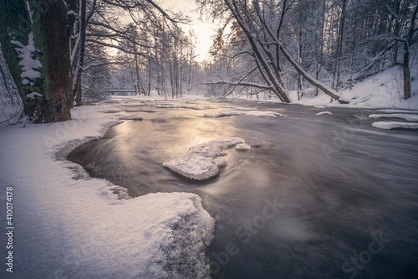 Obraz Scenic winter landscape with flowing river and morning light in Finland. Snowy trees.