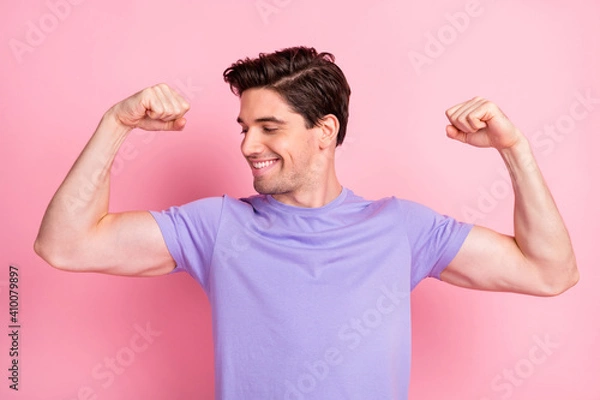 Fototapeta Portrait of nice attractive cheery fit guy demonstrating muscles isolated over pink pastel color background
