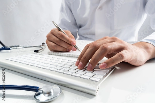 Fototapeta Doctor typing on wireless computer keyboard