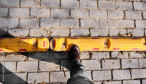 Fototapeta Man boot on the yellow street border with red reflection and cobblestone street in golyazi.