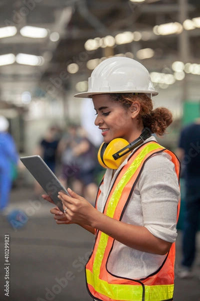 Fototapeta Engineer Female in using Tablet in Foundry worker in factory on the machine. portrait of an industrial Femal engineer with tablet in a factory.