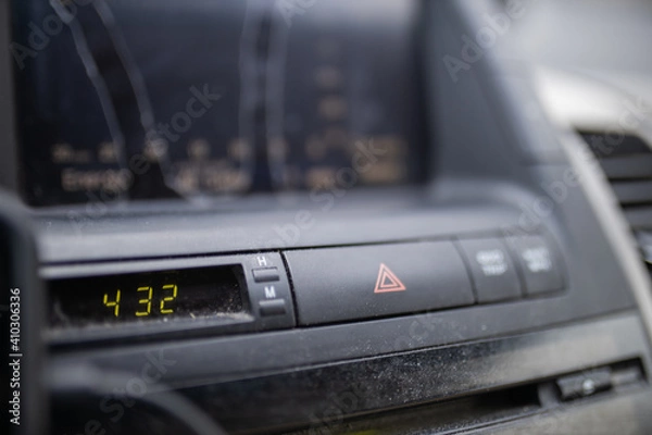 Fototapeta Emergency blinkers button and digital clock on dusty car dashboard