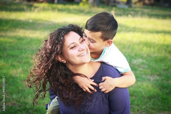 Obraz Happy smiling mixed race mother and son spending time outdoors Cute child hugging and kissing mother