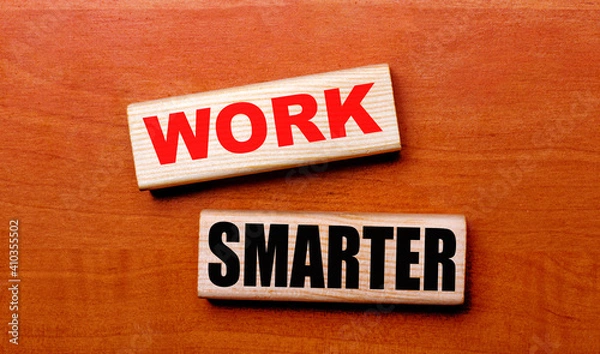 Obraz On a wooden table are two wooden blocks with the text WORK SMARTER