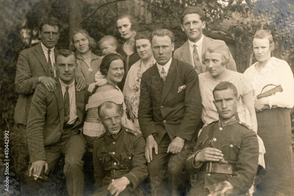 Fototapeta Latvia - CIRCA 1920s: Group photo of party guests. Some men in uniform. Vintage historical archive photo