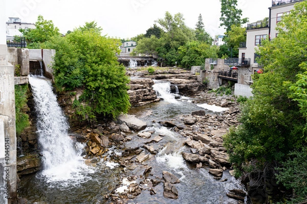 Obraz Almonte Falls, Ontario, Canada, a tiered and multiple segmented waterfall, surrounding small trees and grasses on bedrock during summer.
