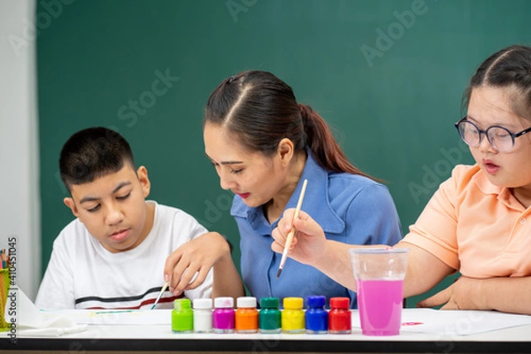 Obraz Asian disability boy learning color Painting in classroom with Autism girl in special school with female teacher.