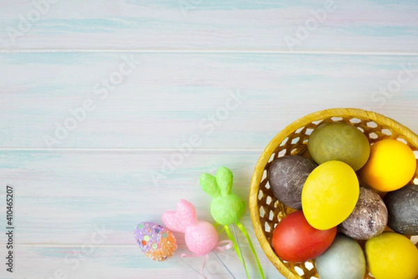 Fototapeta Colored Easter eggs with decor in a wicker yellow basket. Empty space for text
