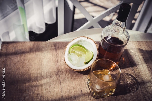 Fototapeta rum with ice and lime in a coconut glass